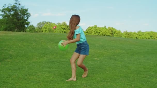 Chica jugando con pelota en el prado verde. Niño caminando sobre hierba en el campo — Vídeo de stock