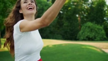 Dışarıda badminton oynayan bir kadın. Badminton raketiyle havaya atlayan kız