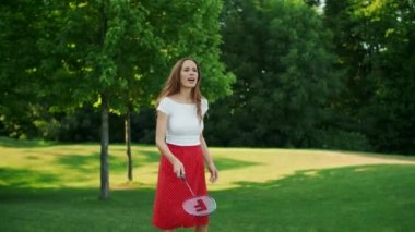 Meadow 'da badminton oynayan kadın. Odaklanmış bir kadın mekiklere bakıyor.