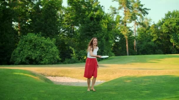 Mulher a jogar frisbee no prado verde. Menina feliz se divertindo no parque — Vídeo de Stock