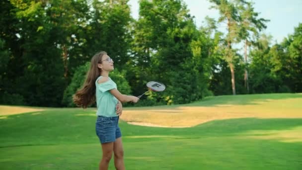 Dívka držící v ruce badmintonovou raketu. Usmívající se teen hrát badminton v parku — Stock video