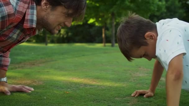 Vater und Sohn machen Liegestütze im Park. Mann und Junge üben Fitnessübungen — Stockvideo