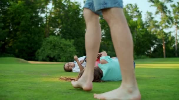 男の子と女の子の芝生の上にフィールドに横たわっている。父と子供たちは公園でボールと遊ぶ — ストック動画