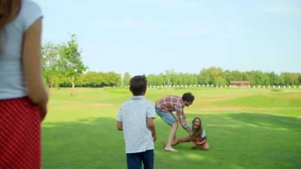 O pai a brincar com a filha no prado. Mulher e menino em pé no campo — Vídeo de Stock