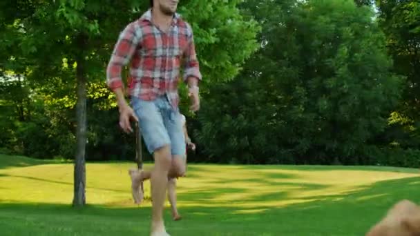 Vidám család fut a zöld mezőn. A terepen játszó gyerekek és szülők — Stock videók