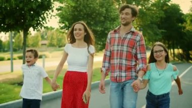 Gülümseyen aileler ve parkta yürüyen çocuklar. Neşeli aile el ele tutuşuyor