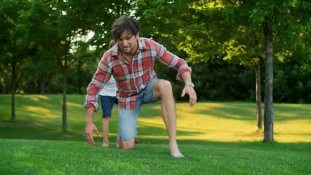 Zoon springt op vader terug in Green Park. Vreugdevolle man geven jongen piggyback paardrijden — Stockvideo