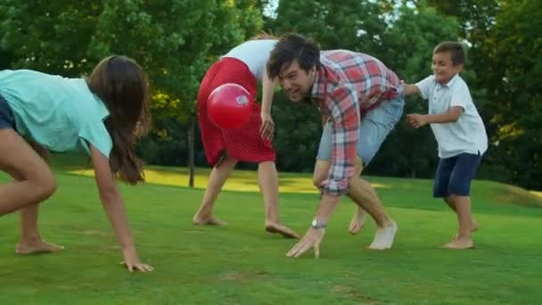 Padres e hijos jugando con pelota en el prado. familia disfrutando de actividades al aire libre — Vídeos de Stock