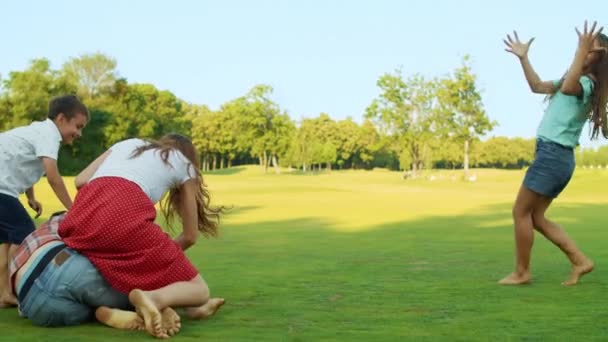 積極的な家族の牧草地でボールと遊ぶ。幸せな男は女の子にボールを投げる — ストック動画