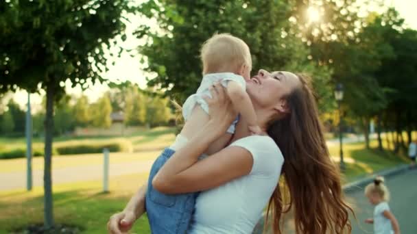 Een vrouw op straat met een kleine jongen. Moeder houdt zoon op handen in het park — Stockvideo