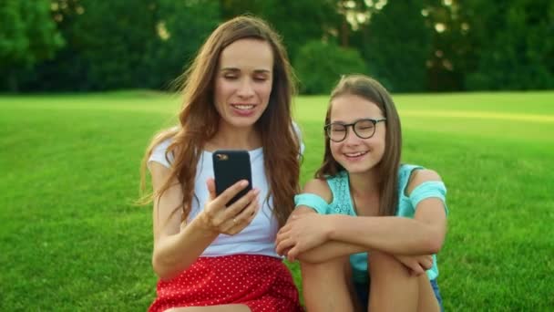 Anne ve kızı akıllı telefondaki görüntülü konuşma sırasında kameraya el sallıyor. — Stok video