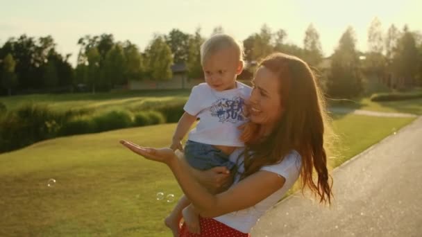 Žena držící chlapce za ruce. Batole s matkou hraje s mýdlovými bublinami — Stock video