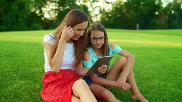 Vrouw en meisje met behulp van tablet. Moeder en dochter surfen op internet op pad — Stockvideo