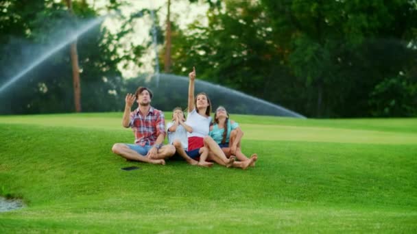 Familia con la tableta sentada en la hierba. Niños y padres pasando tiempo juntos — Vídeos de Stock