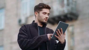 Dışarıdaki tablet ekranı gören şaşırmış bir adam. Dijital tablet kullanan mutlu adam