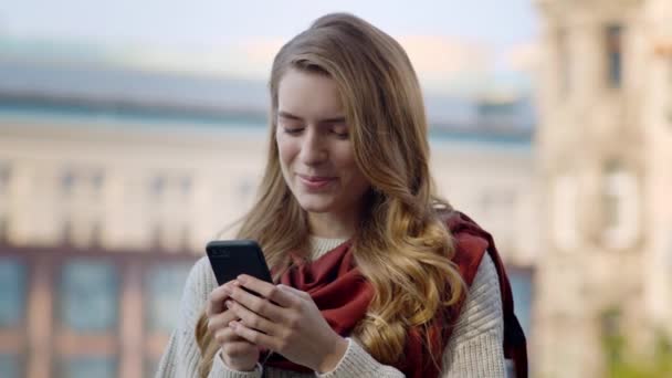 Fröhliches Mädchen mit dem Handy im Freien. Lächelnde Frau steht mit Handy auf der Straße. — Stockvideo