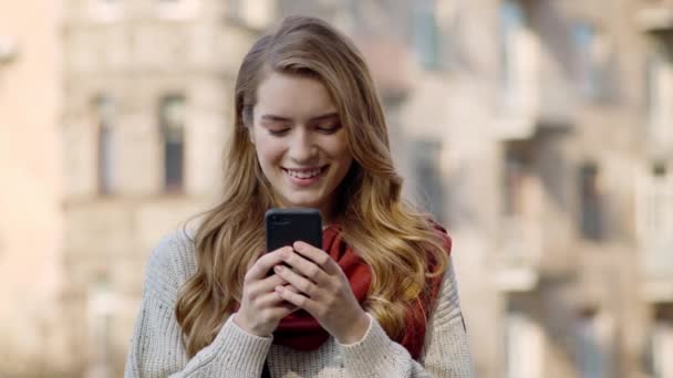 Mulher feliz enviando mensagens por telefone ao ar livre. Sorrindo menina recebendo mensagem na rua — Vídeo de Stock