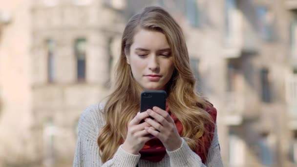 Schöne Frau mit Telefon im Freien. Hübsches Mädchen sucht Handy-Bildschirm auf der Straße — Stockvideo