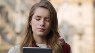 Tableti açık havada tutan düşünceli bir kadın. Ciddi kız görünümlü tablet ekranı
