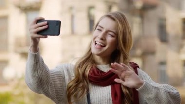 Hippi kadın telefonla video görüşmesi yapıyor. Neşeli kız dışarıda telefon kullanıyor.