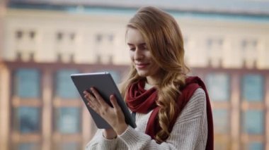 Açık havada tablet kullanan güzel bir kadın. Sokakta tablete dokunan gülümseyen kız.