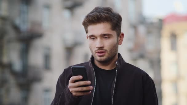 Upset man using phone outside. Disappointed guy receiving message outdoors — Stock Video