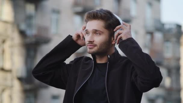 Dışarıda müzik kulaklığı dinleyen neşeli bir adam. Kulaklık kullanan rahat bir adam. — Stok video