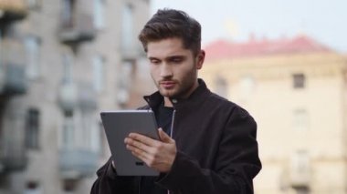 Dışarıda tablet kullanan üzgün bir adam. Dışarıya bakan ciddi adam.