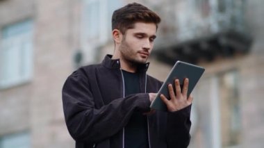 Tablet ekranı gibi yakışıklı bir adam. Genç adam dijital tablete dokunuyor.