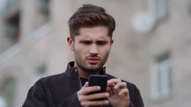 Homme ennuyé utilisant un smartphone à l'extérieur. Nerveux gars regardant écran de téléphone à l'extérieur. — Video