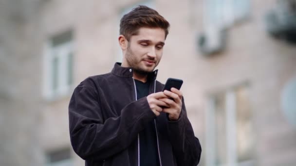 Un homme heureux qui utilise son téléphone dehors. Souriant gars bavarder via téléphone à l'extérieur. — Video