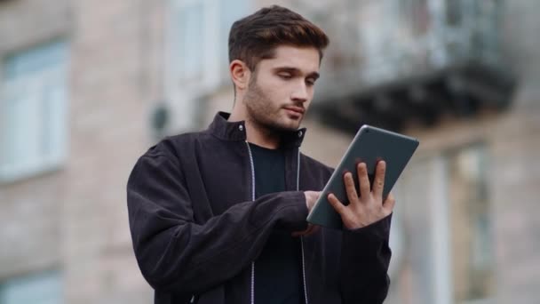 Flot fyr, der ser tabletskærm udendørs. Ung mand rører digital tablet. – Stock-video