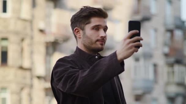 屋外でビデオ通話をしている笑顔の男。興奮した男は外で電話画面を見て — ストック動画