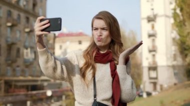 Hippi kız dışarıda selfie çekiyor. Flört eden kadın kamera için yüzünü buruşturuyor.
