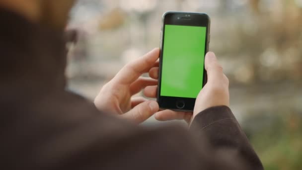 Man handen die een groen scherm vasthouden. Guy op zoek telefoon chroma sleutel scherm — Stockvideo