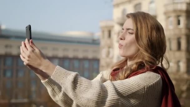 Linda chica haciendo foto selfie al aire libre. Mujer divertida usando el teléfono celular en la calle . — Vídeo de stock