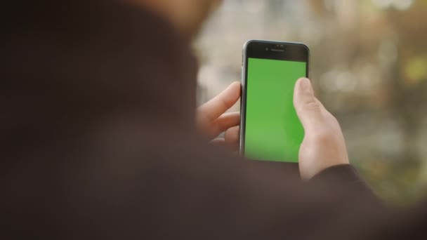 Hombre desplazándose pantalla verde smartphone. Chico navegando por internet maqueta de teléfono celular — Vídeo de stock