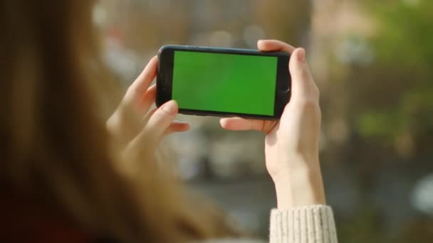 Vrouw op zoek telefoon groen scherm. Close-up meisje met behulp van telefoon met chroma sleutel. — Stockvideo