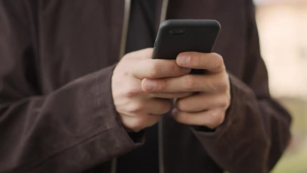 Manos masculinas usando teléfono móvil al aire libre. Chico desconocido enviando mensajes de teléfono afuera — Vídeos de Stock