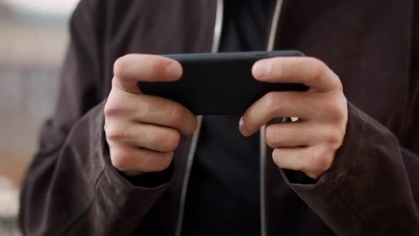 Gros plan gars jeu téléphone portable à l'extérieur. Les mains de l'homme jeu de téléphone portable. — Video