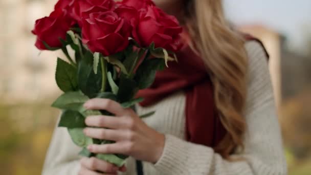 Mani di donna che portano rose in faccia. Ragazza allegra che odora fiori all'aperto — Video Stock