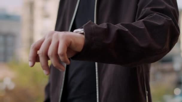 Σοβαρός άνθρωπος ελέγχει το χρόνο στο χέρι ρολόι στο δρόμο. Κοντινό χέρι άνθρωπος με ρολόι. — Αρχείο Βίντεο