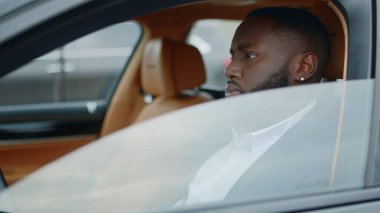 Afrikalı bir adam arabanın camını indiriyor. Arabada oturan Afrikalı bir adam..