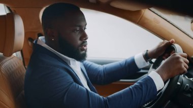 Yan görüşlü adam direksiyonda oturuyor. Arabada dans eden Afrikalı adam.