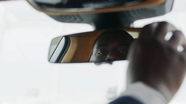 Closeup man adjusting rear view mirror at car. African man sitting front at car