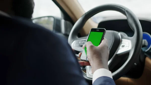 Людина заднього виду використовує телефон з зеленим екраном. Чоловік вводить смартфон у машину — стокове фото