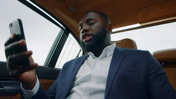 Primer plano hombre africano teniendo videollamada en el coche. Hombre de negocios hablando de teléfono en el coche —  Fotos de Stock