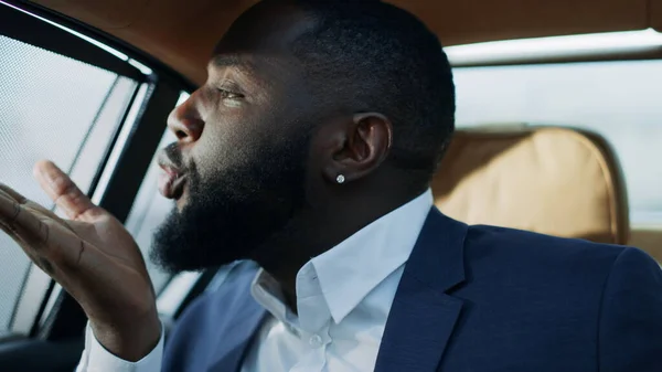 Retrato del hombre africano soplando beso en el asiento trasero en el coche. Hombre de negocios coqueteando —  Fotos de Stock