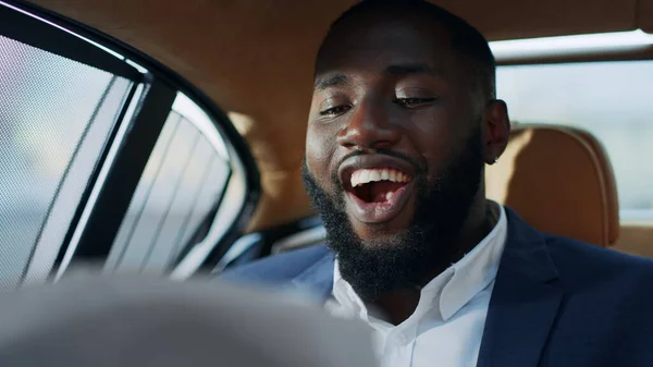 Retrato del alegre hombre de negocios africano que busca documentales ficticios en el coche . —  Fotos de Stock