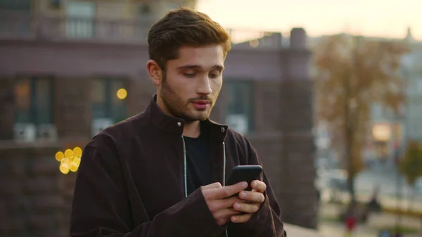 Happy man looking phone screen on street. Smiling guy catting by phone outdoors. — Stock Photo, Image